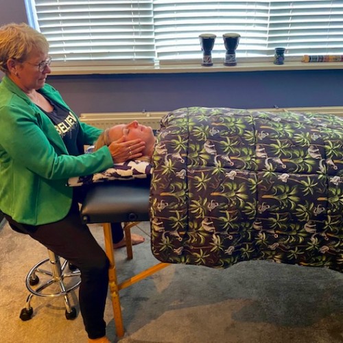 Annelies behandelt haar klant met Reiki terwijl die diep ontspant onder een warme deken